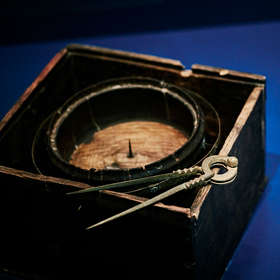 A set of dividers sitting on a compass, both items from the Mary Rose